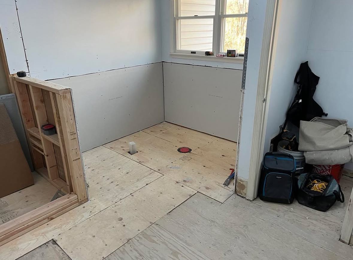 Before: the same bathroom stripped to plywood subfloor and bare board